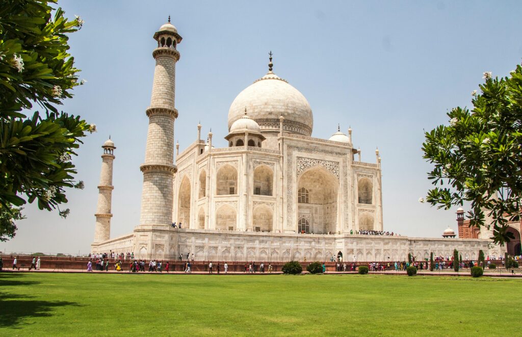Iconic Taj Mahal showcasing its white marble beauty and lush gardens on a sunny day.