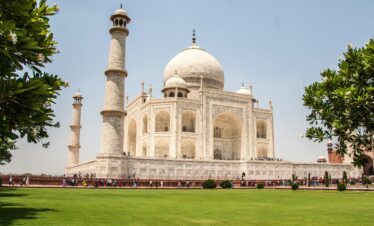 Iconic Taj Mahal showcasing its white marble beauty and lush gardens on a sunny day.