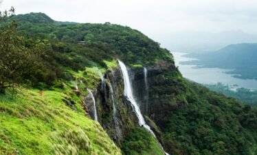 Breathtaking view of a waterfall in Matheran, India surrounded by lush greenery and serene mountains.