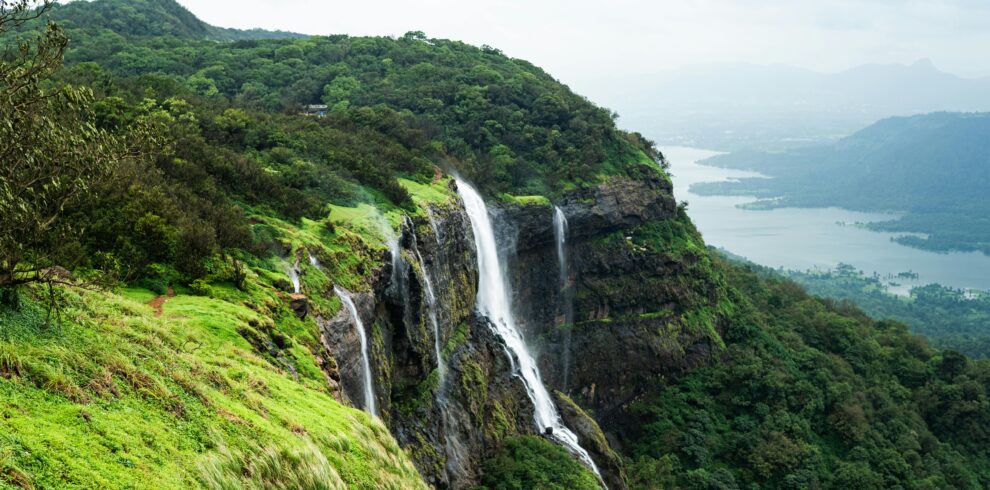 Breathtaking view of a waterfall in Matheran, India surrounded by lush greenery and serene mountains.